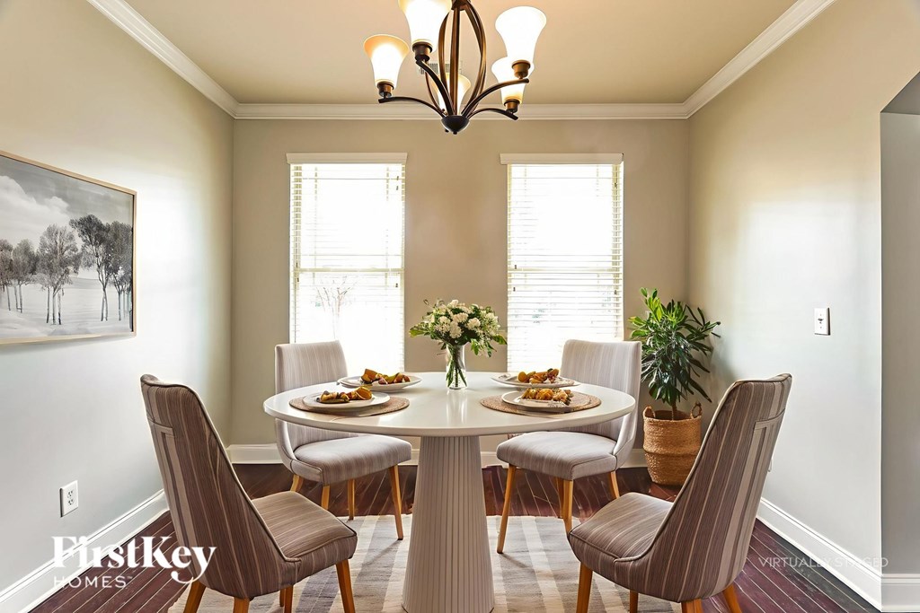 A dining room with a table set for six and a chandelier hanging from the ceiling.