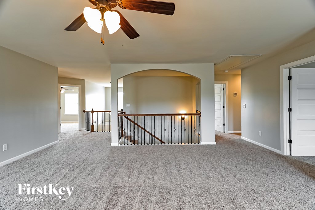 A spacious living room with a fan and carpeted floor.