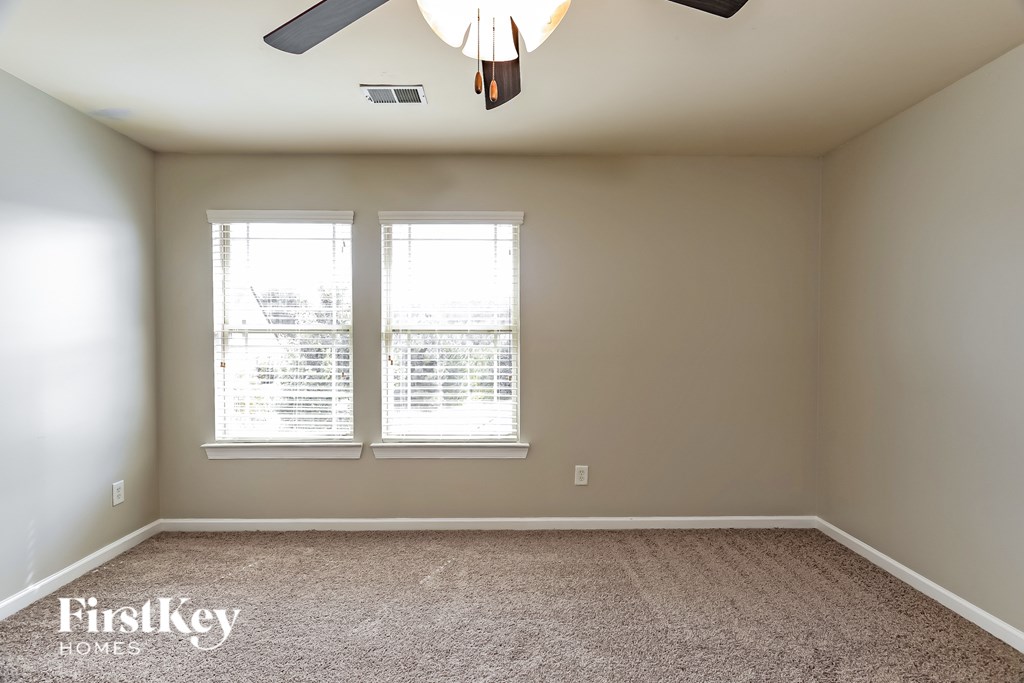 A room with a carpet floor, a ceiling fan, and a window with blinds.