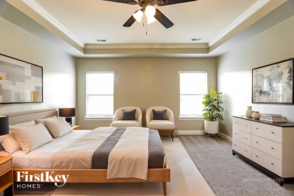 A bedroom with a large bed, two chairs, and a dresser.