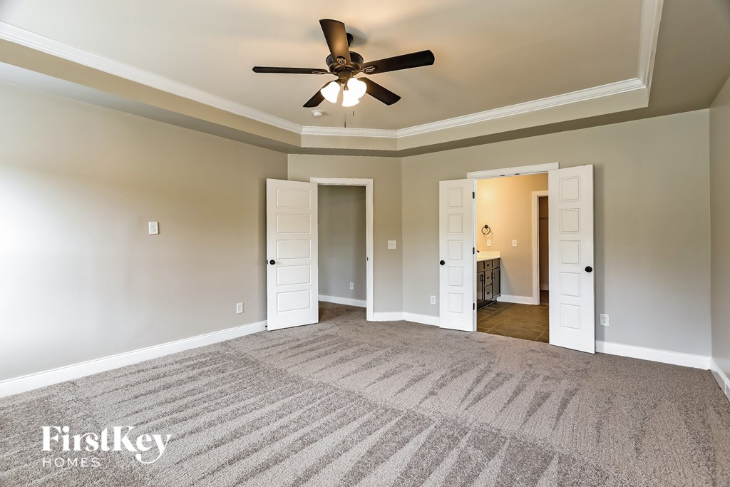 A spacious room with a ceiling fan and carpeted floor.