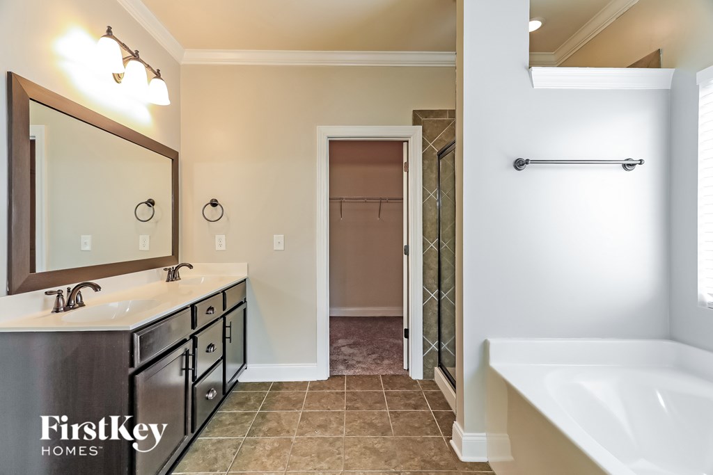 A bathroom with a tub, sink, mirror, and towel rack.
