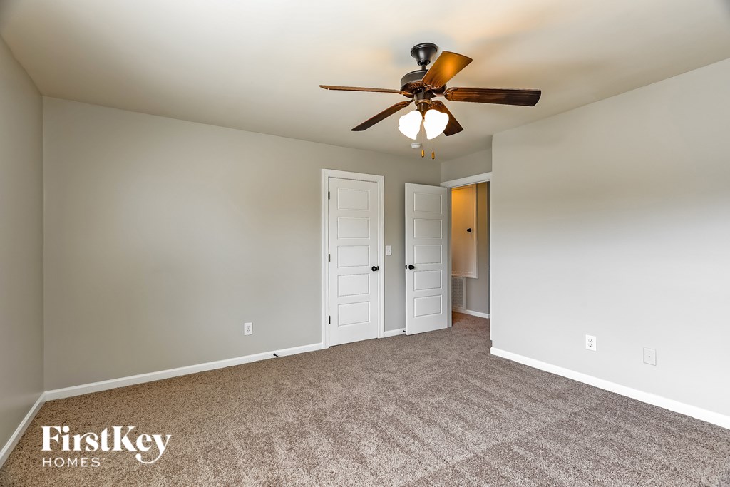 A room with a carpeted floor and a ceiling fan.