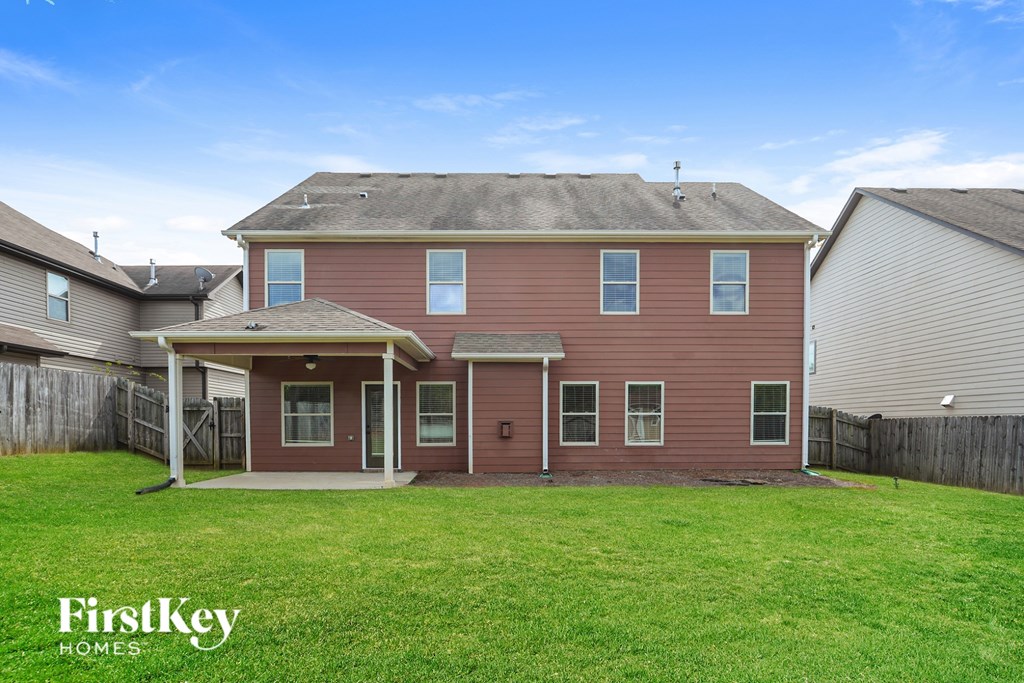 A red house with a white fence and a green lawn.
