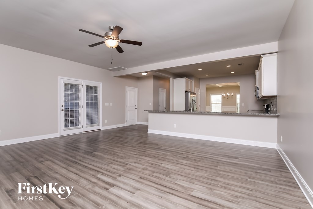A spacious room with a ceiling fan and wooden flooring.