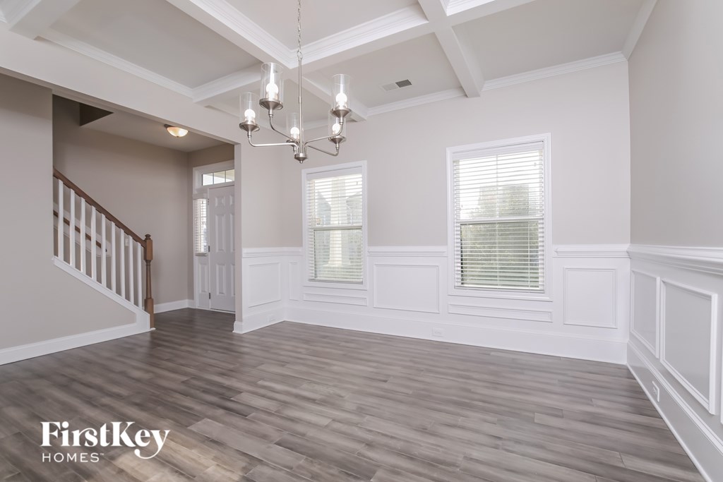A spacious room with wooden floors and a staircase on the left side.