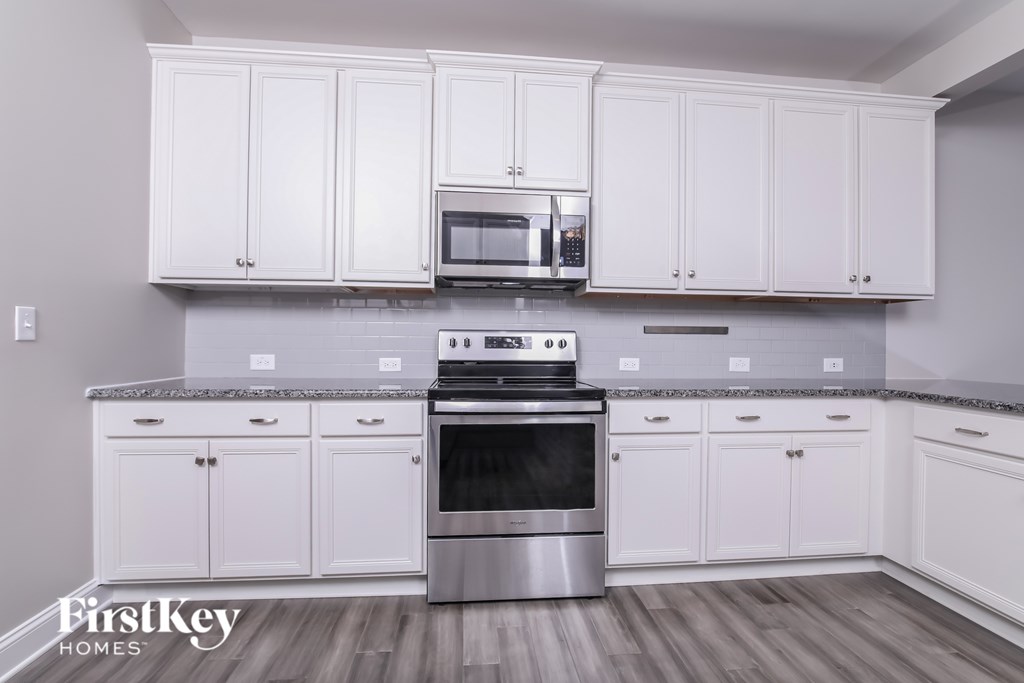 A kitchen with white cabinets and a stainless steel oven.