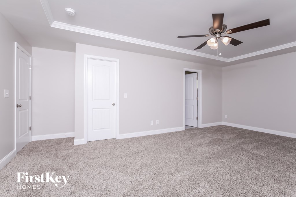 A room with a ceiling fan and carpeted floor.