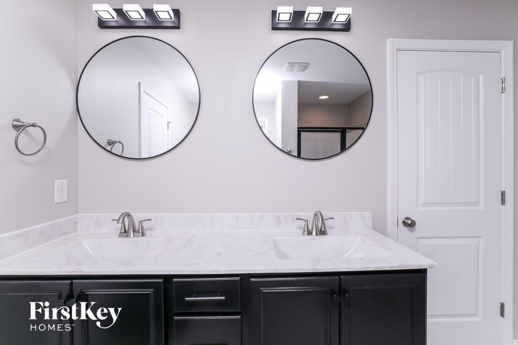 A bathroom with a marble countertop and two round mirrors above it.