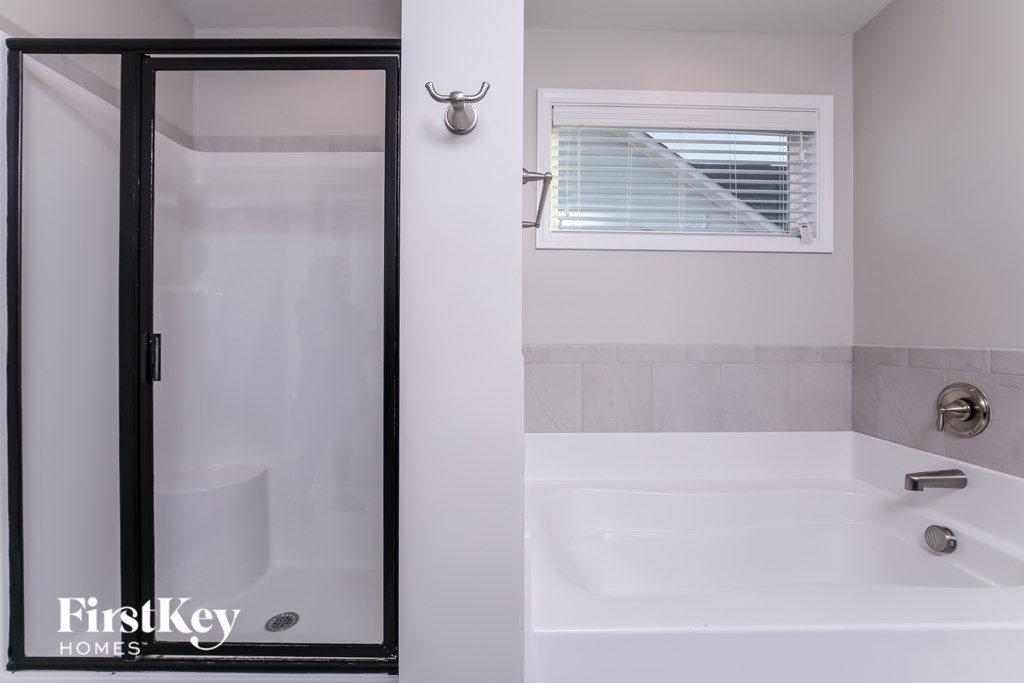 A white bathtub with a black shower door in a bathroom.