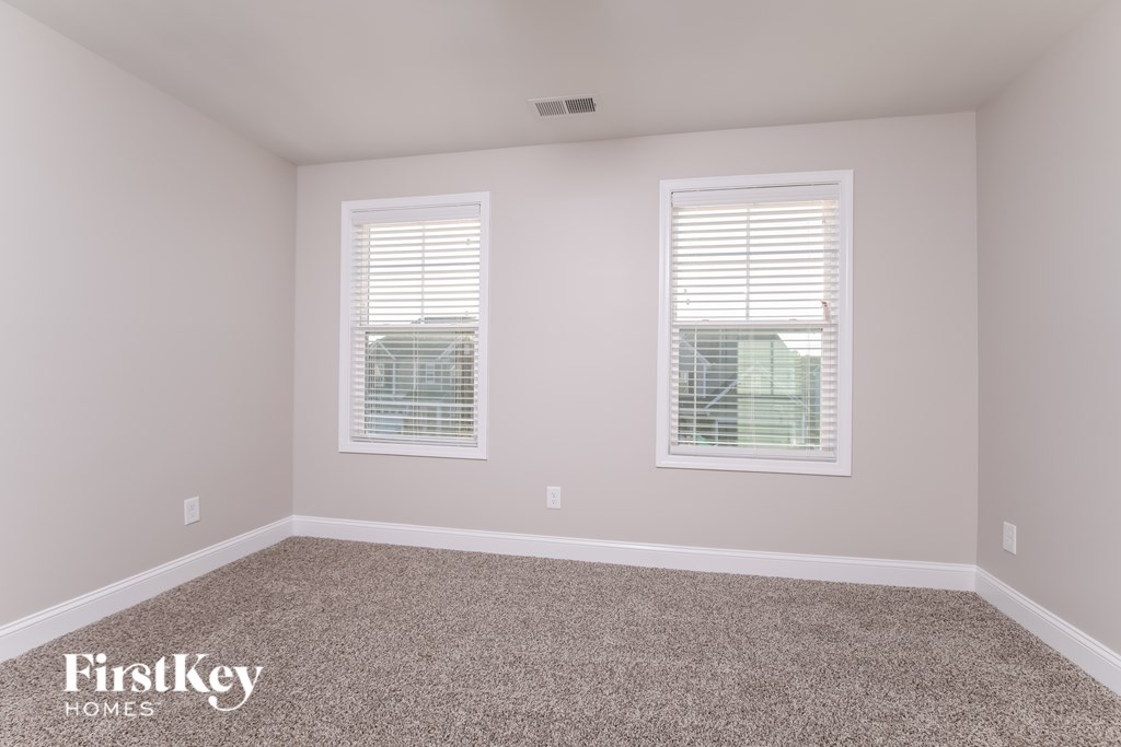 A room with two windows and a carpeted floor.