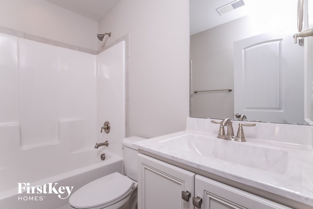 A white bathroom with a toilet, sink, and mirror.