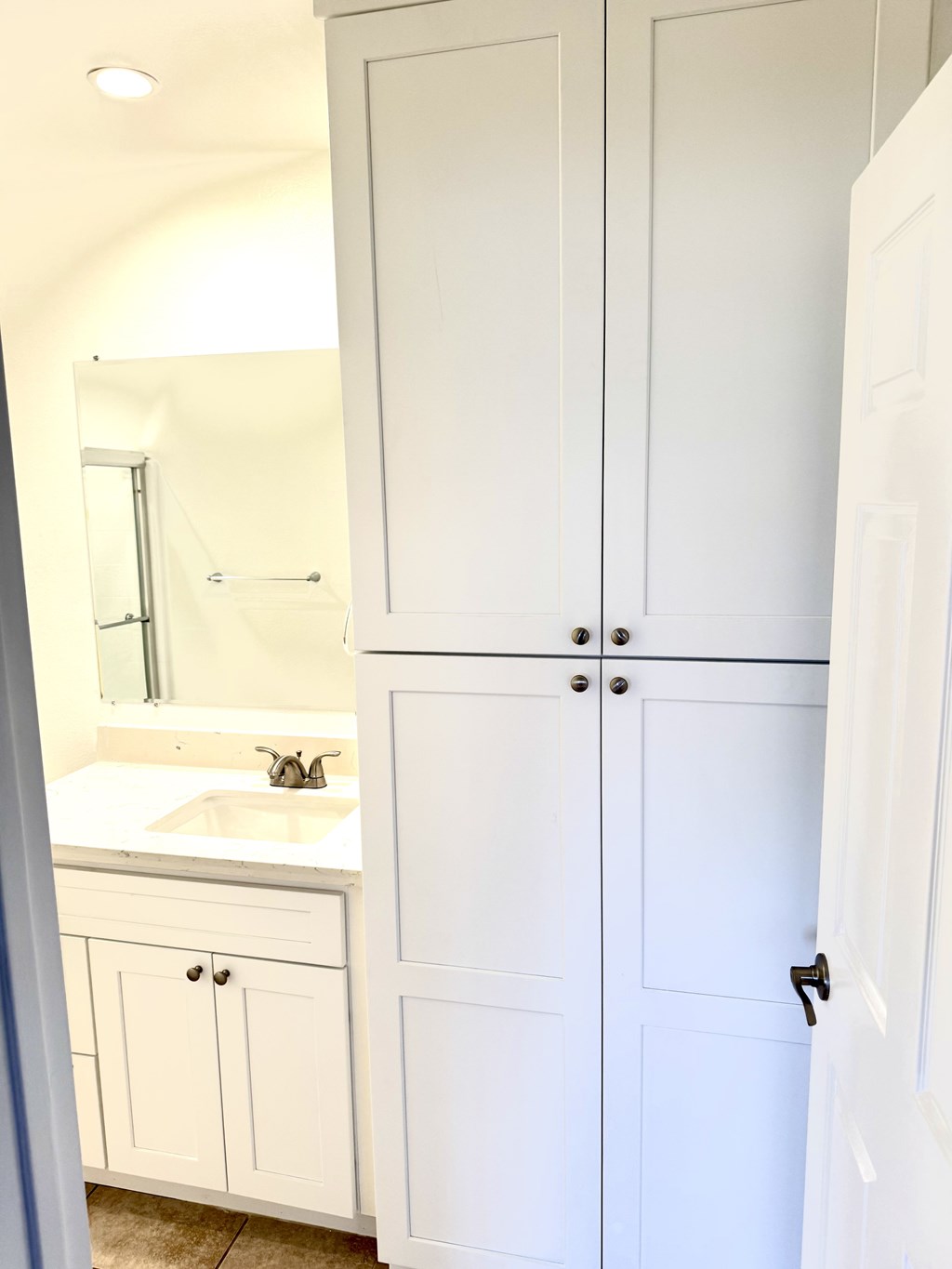 A white bathroom with a sink and cabinets.