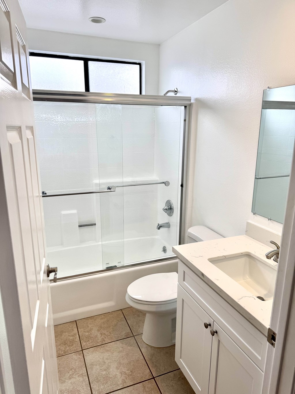 A white bathroom with a toilet, sink, and shower.
