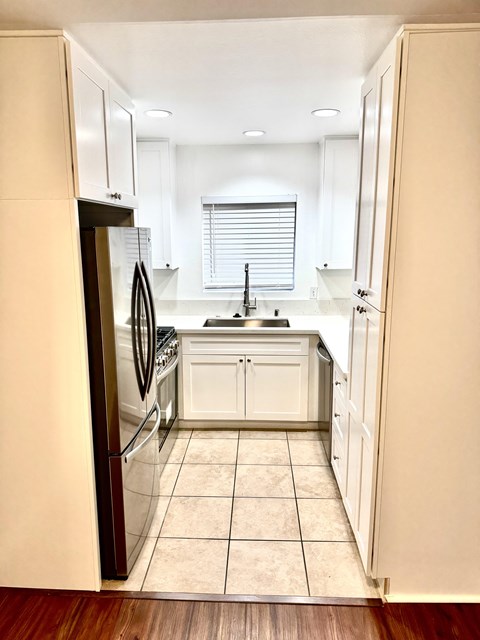 A kitchen with white cabinets and a black refrigerator.