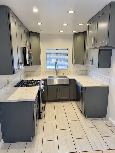 A kitchen with a sink, stove, and cabinets.