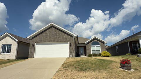 A house with a grey garage door and a white car parked in front.