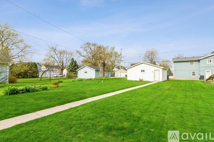 A grassy area with a pathway and houses in the background.