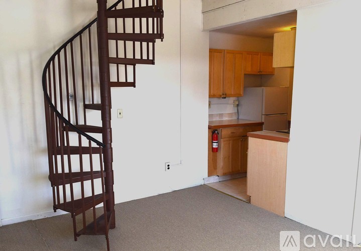 A spiral staircase in a room with a kitchen in the background.
