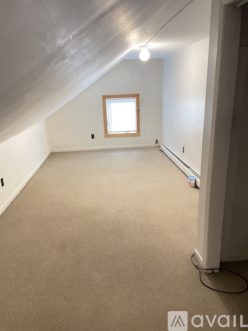 A room with a window and a carpeted floor.