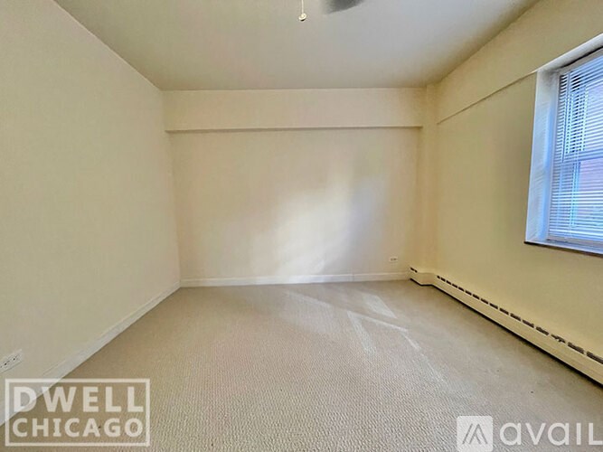 A room with a window and a carpeted floor.