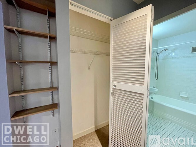A white closet with a sliding door is open to a bathroom.