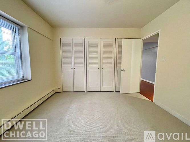 A room with white walls and a carpeted floor with a window on the left side.