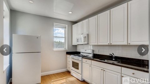 A kitchen with white cabinets and a black countertop.