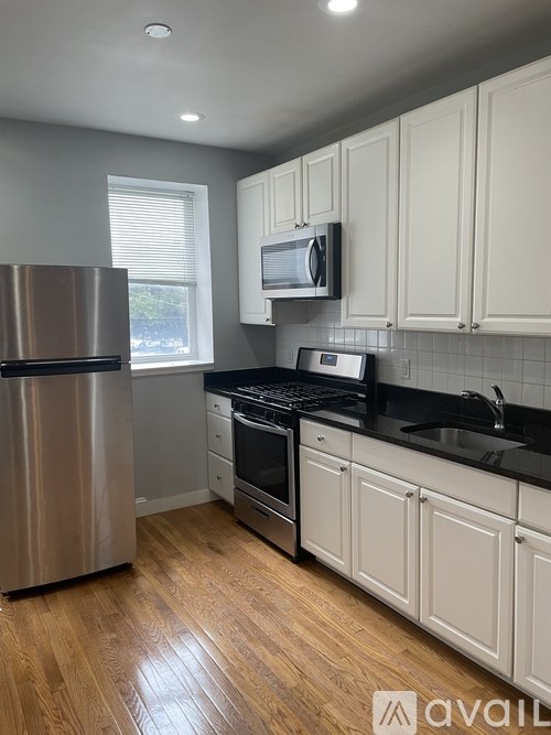 A kitchen with white cabinets and a black countertop.