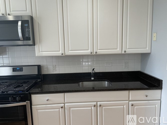 A kitchen with white cabinets and black appliances.