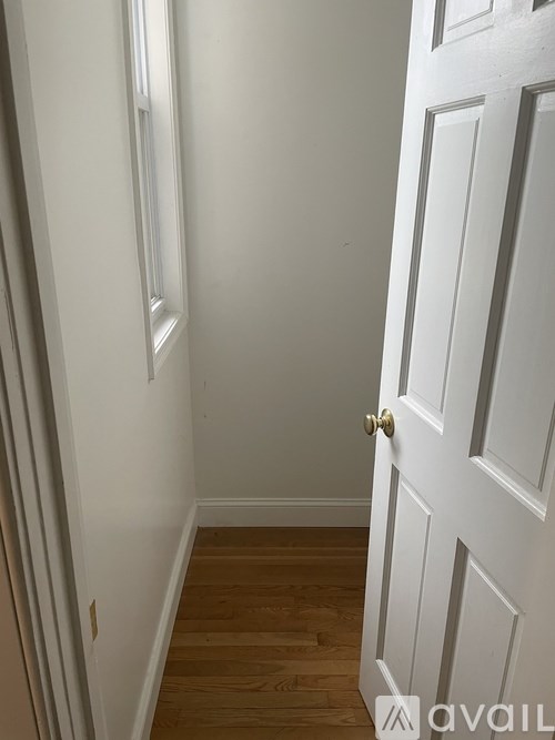A white door with a gold handle is in a room with wooden floors.