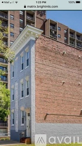 A tall building with a brick facade and a grey section with windows.