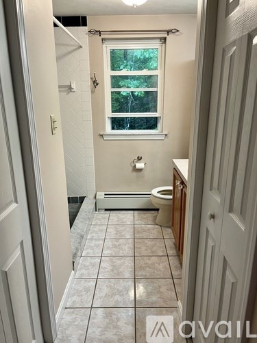 A bathroom with a toilet, sink, and window.