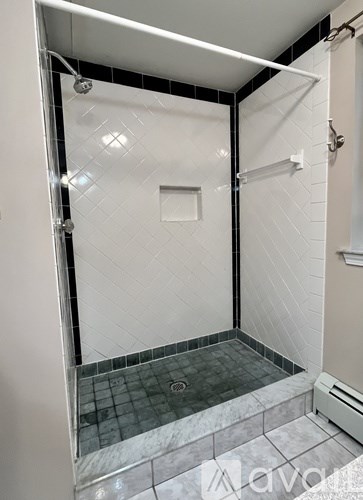 A shower area with a glass door and a tiled floor.