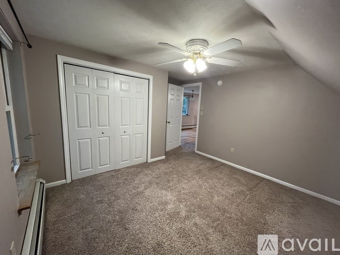 A room with a carpeted floor and a ceiling fan.