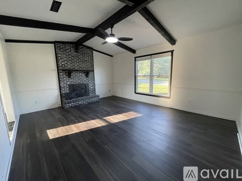 A spacious room with a fireplace and wooden flooring.