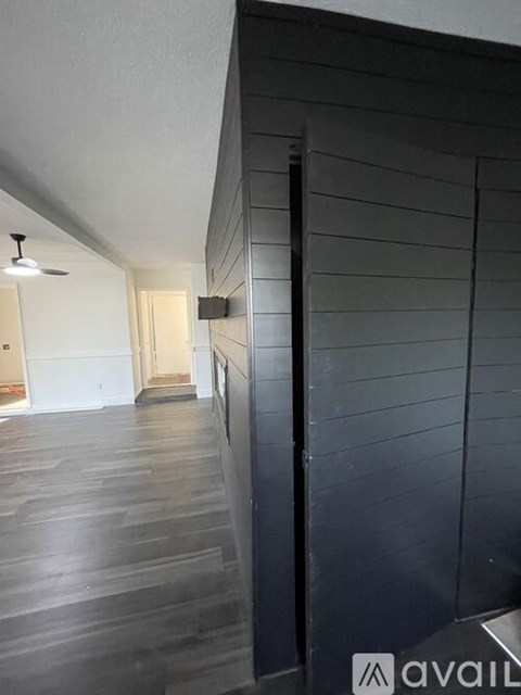 A hallway with a black wall on the right and a white door at the end.