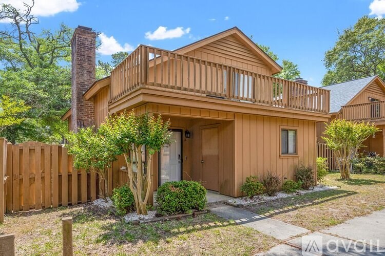 A wooden house with a balcony and a tree in front.