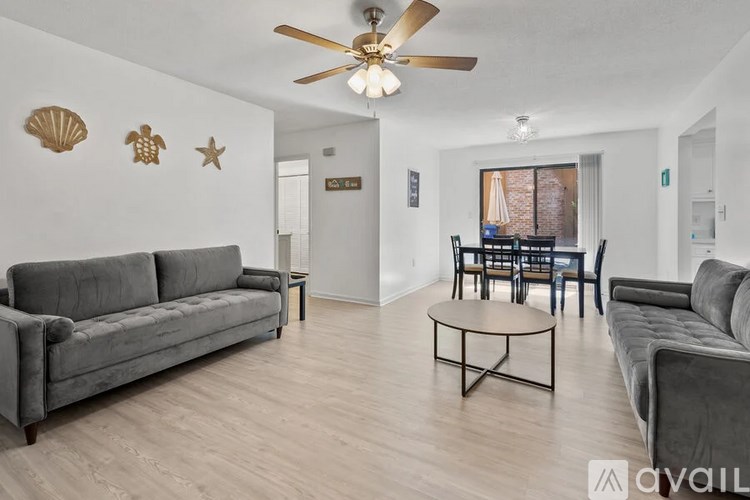 A living room with a grey couch, a coffee table, and a ceiling fan.