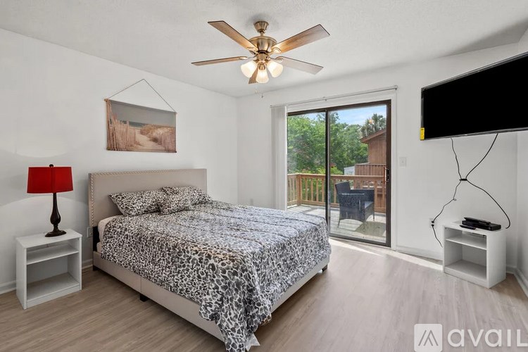 A bedroom with a bed, a ceiling fan, and a television.