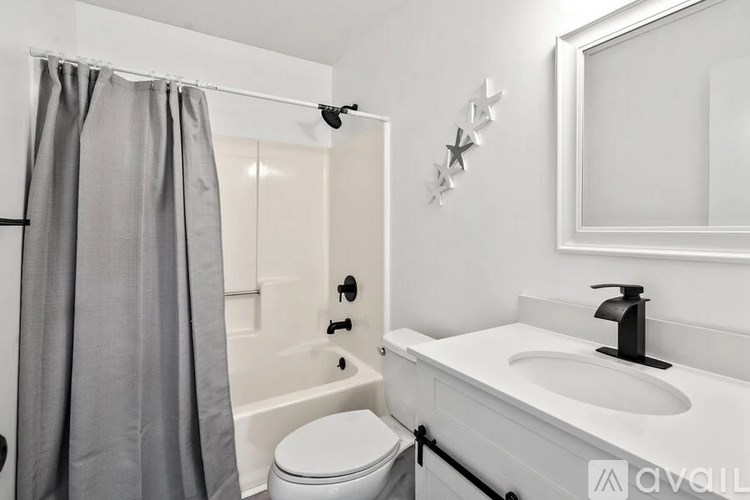 A bathroom with a white toilet, a white sink, and a grey shower curtain.