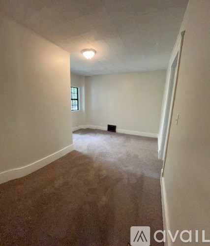 A room with a carpeted floor and a window.