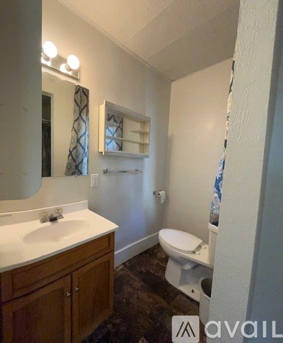 A bathroom with a toilet, sink, and mirror.