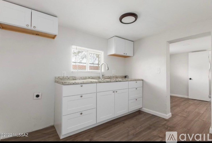 A kitchen with white cabinets and a window.