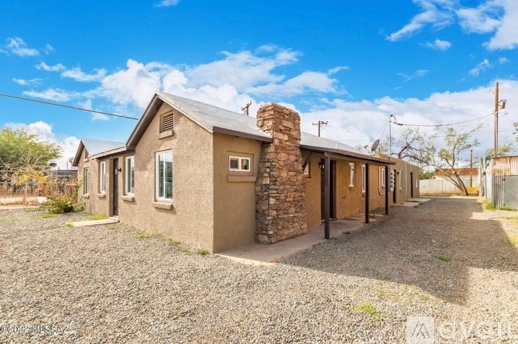 A house with a gravel driveway and a stone chimney.
