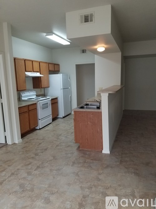 A kitchen with a refrigerator, sink, and cabinets.