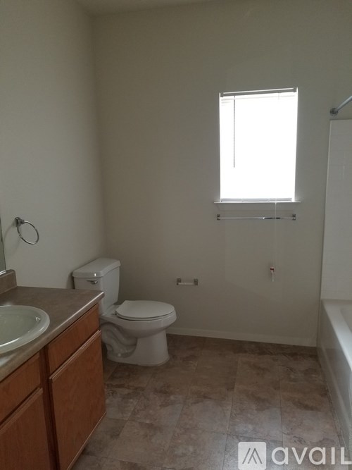 A bathroom with a toilet, sink, and window.