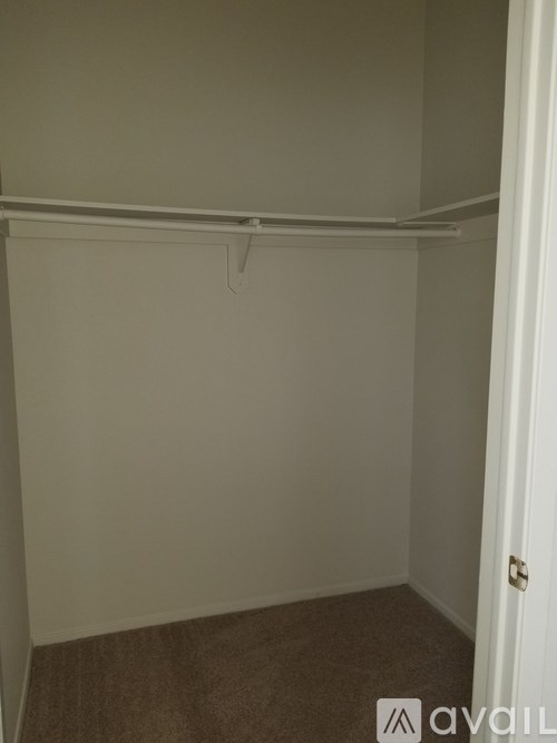 A small, empty room with a carpeted floor and a white door.