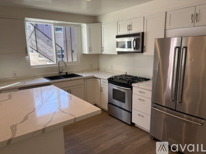 A kitchen with a white countertop and wooden flooring.