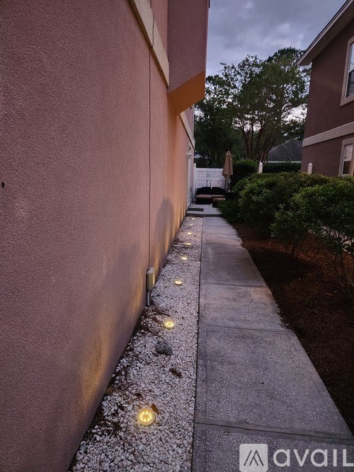 A sidewalk with lights and a wall on the left.
